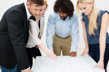 Dedicated business team working on paperwork as they stand grouped around a table together having a brainstorming session